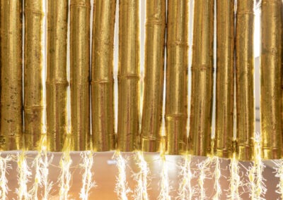 a close up shot looking out from inside a 2m bamboo art installation made into a round shelter with a front opening of thin yellow wool people can climb into. There is also gold leaf applied to the bamboo.