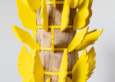 a sculpture made of a found wooden stump and then 6 layers of bright yellow ply. Those layers have bright yellow ply wings extended outwards