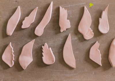 an above shot taken of unfired clay wings of different shapes on a brown board